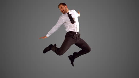businessman jumping and stretching on grey background