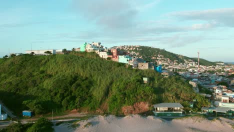 pequeña favela, casas humildes construidas en una colina tropical en arraial do cabo, barrios marginales costeros de brasil, toma aérea de drones