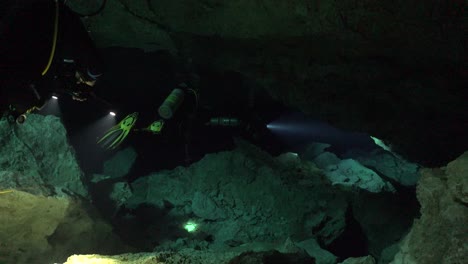 Buceadores-Nadando-A-Través-Del-Sistema-De-Cuevas-Cenotes-Tajma-Ha-En-Yucatán-México-Formaciones-Rocosas-De-Iluminación-Con-Linternas-Submarinas