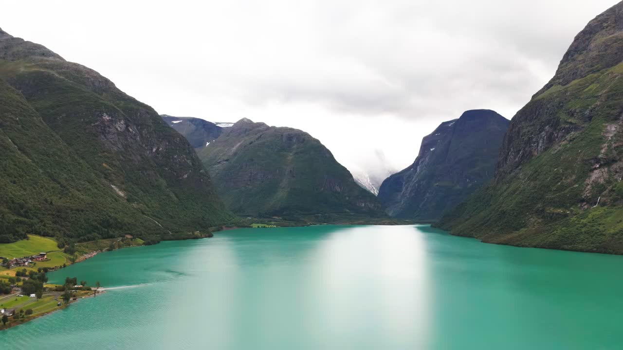 Aerial panoramic dolly over Lake Lovatnet in Norway, with its crystal-clear turquoise waters and surrounding mountains