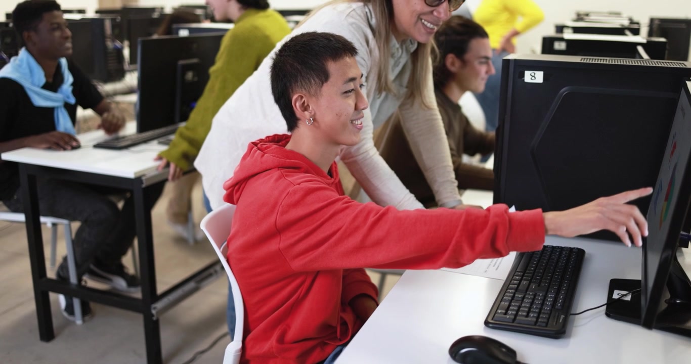 Teacher Assisting Student with Computer Work in Classroom