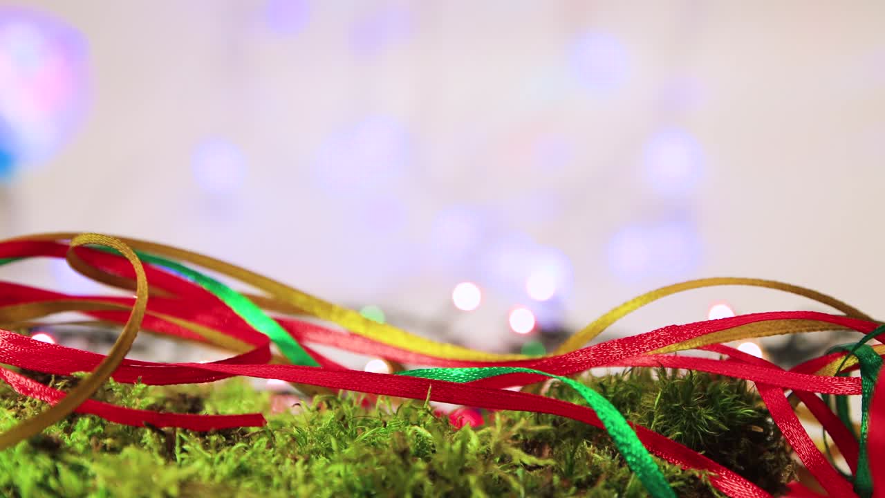 Colored ribbons on green moss, Christmas tree decoration with bokeh back.