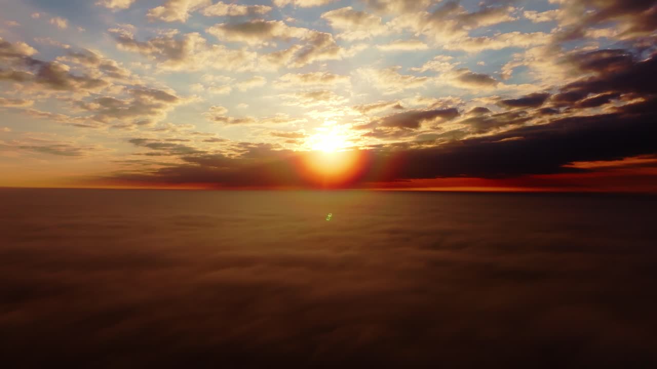 Dramatic aerial shot lifts above thick clouds revealing golden sun at sunrise