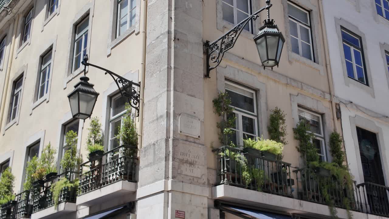 Lisbon Rua Augusta corner building with iron lanterns and potted balcony greenery