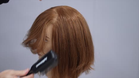 hair styling demonstration on a mannequin head with a bob cut