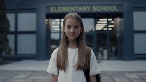 cute shy girl standing at school entrance alone. portrait pretty schoolgirl.