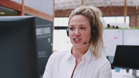 female customer services agent working at desk in call center