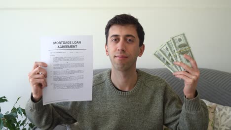 concept of getting a mortgage loan to buy a real estate. man holding agreement document and cash