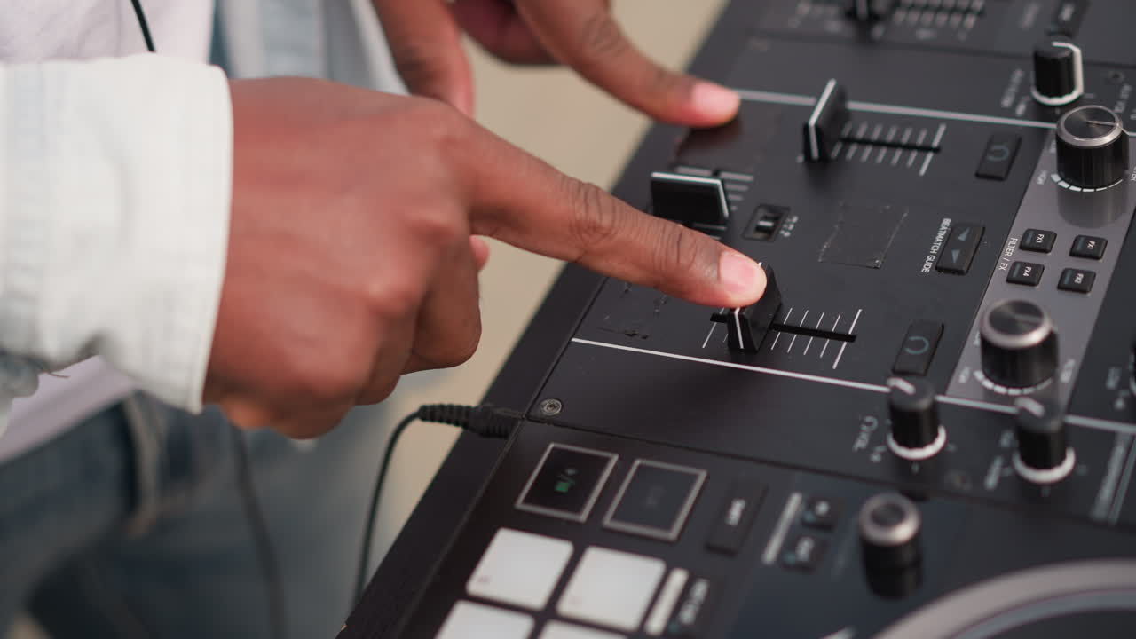 DJ noir dynamique mixant en direct avec le crossfader, ses mains glissant sur le fader et tapant sur les pads. Une veste en jean est visible. Il utilise un mixeur portable doté de boutons et de curseurs, dégageant l'énergie d'un set de rue sur un toit, avec des transitions rythmiques.