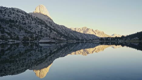 Serene mountain landscape reflecting on calm Rae Lakes at sunrise in the John Muir Trail