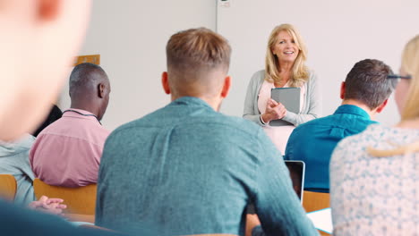 Female-College-Tutor-With-Digital-Tablet-Teaches-Mature-Students