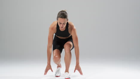 Young-Caucasian-woman-athlete-in-athletic-wear-prepares-to-run-on-a-white-background,-with-copy-spac