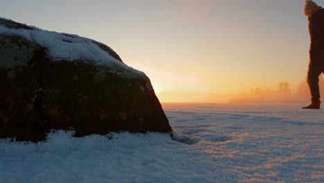 hombre solo caminando sobre hielo congelado al atardecer dorado, invierno nevado en el paisaje ártico