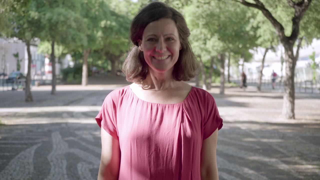 una hermosa mujer de mediana edad posando en un parque de verano.
