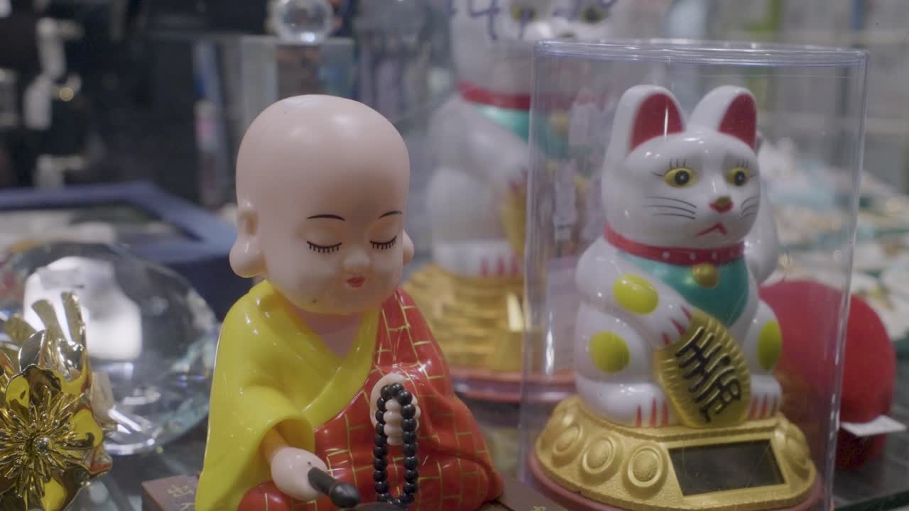 Small Buddha figurine and a Maneki Neko cat in a vibrant souvenir display