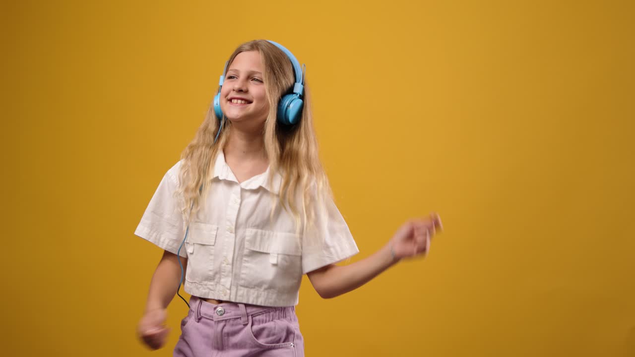Girl dancing with headphones on yellow background