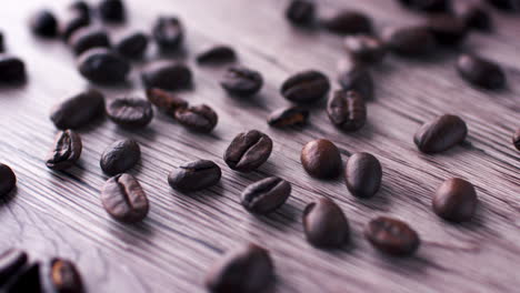 coffee beans on a wooden surface being swiped away by a hand