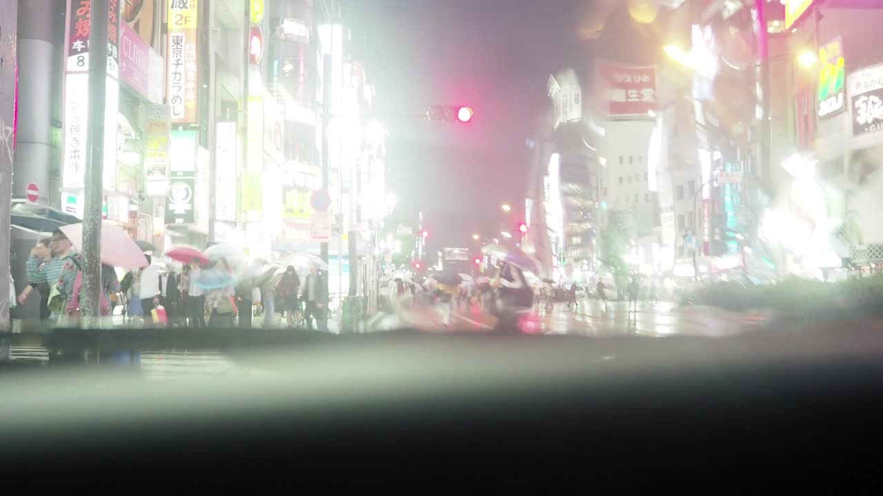 비가 내리는 도쿄 신주쿠의 교차로를 건너는 사람들