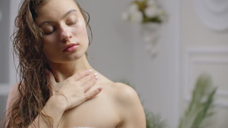 belleza y cuidado corporal dolor de codo femenino y concepto de cuidado de la salud. movimiento lento de la mujer caucásica aplicando loción crema hidratante relajándose en la cama en el apartamento acogedor blanco cerca de la ventana. mano tocando con cuidado