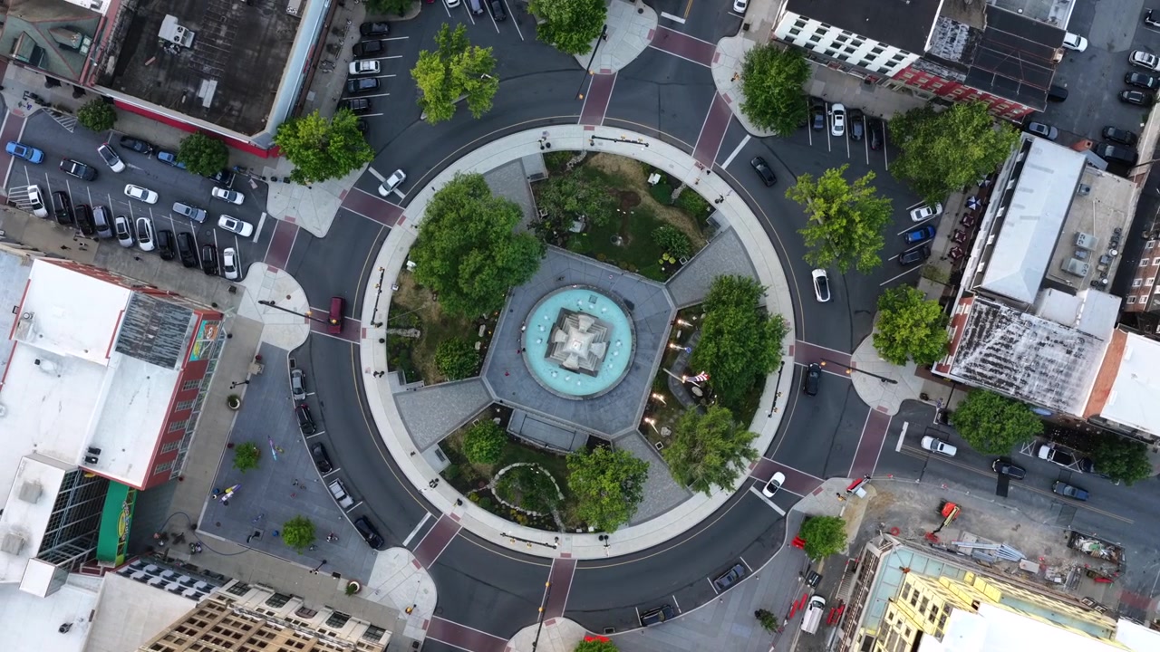 Piazza circolare con fontana è il fulcro della rotonda del traffico nel centro di Easton, Pennsylvania; le auto circolano in un anello alberato oltre densi edifici in mattoni e strisce pedonali dipinte sottostanti. Vista aerea dall'alto con drone
