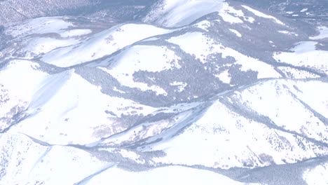 Una-Vista-Aérea-De-Las-Montañas-Cubiertas-De-Nieve-Que-Se-Inclinan-Hacia-Las-Mesas-Desérticas-Del-Suroeste-De-EE.UU.