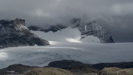 thick low clouds casting shadows on the brilliant white of the glacier