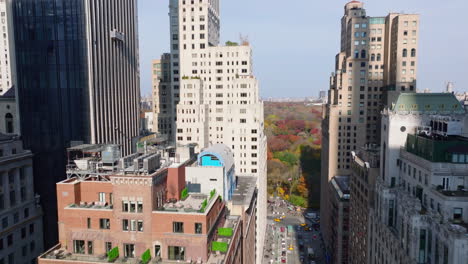 Adelante-Vuelan-Entre-Los-Edificios-Del-Centro-De-Gran-Altura.-Reveladora-Vista-Panorámica-Del-Parque-Central-De-Otoño.-Manhattan,-Ciudad-De-Nueva-York,-Estados-Unidos