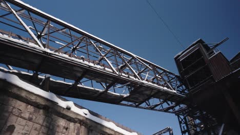 old rusted metal industrial structure with a lattice structure bridge and brick tower covered in snow