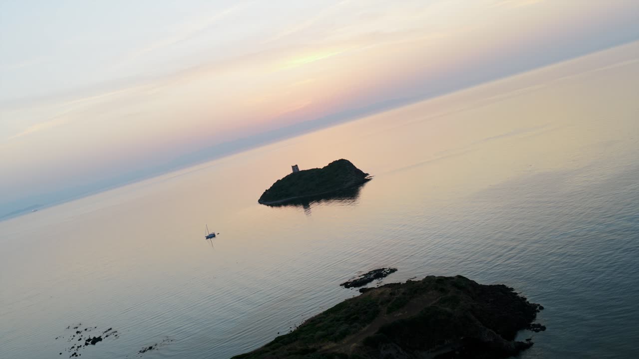 Sunset on coast of Pula, sailboat floats on calm Mediterranean Sea, Sardinia, Italy. Aerial drone, copy space