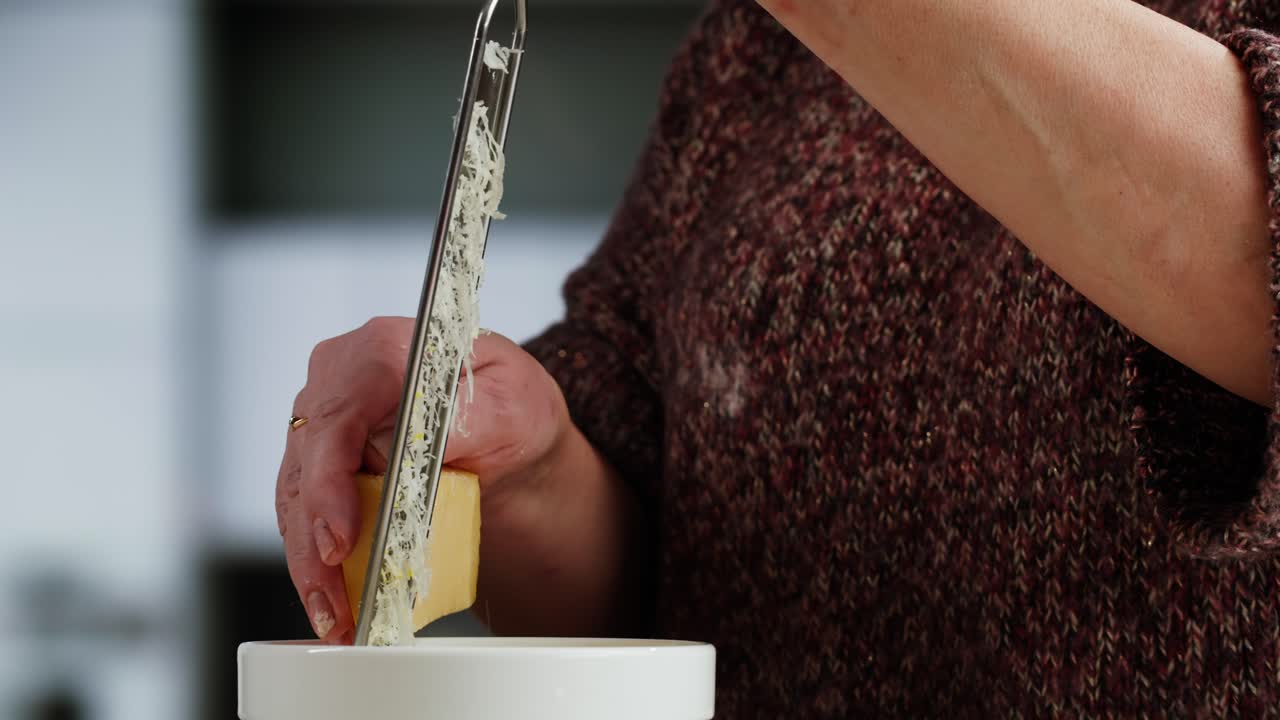 Close-Up of Person Grating Cheese into a White Bowl