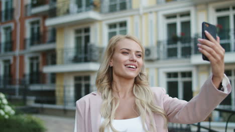 portrait woman using video call outside. businesswoman walking in pink suit