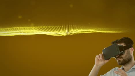 caucasian man wearing vr headset against golden digital waves and light spots on yellow background