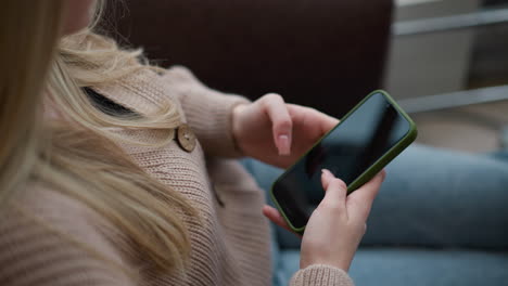 close-up of lady seated in modern mall, holding phone showing a picture, soft focus on her hand and phone, with cozy interior ambiance and a blurred background of mall space