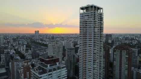 Urban-high-rise-built-structure-in-dense-Buenos-Aires-skyline-at-sunset-Aerial-rising-view