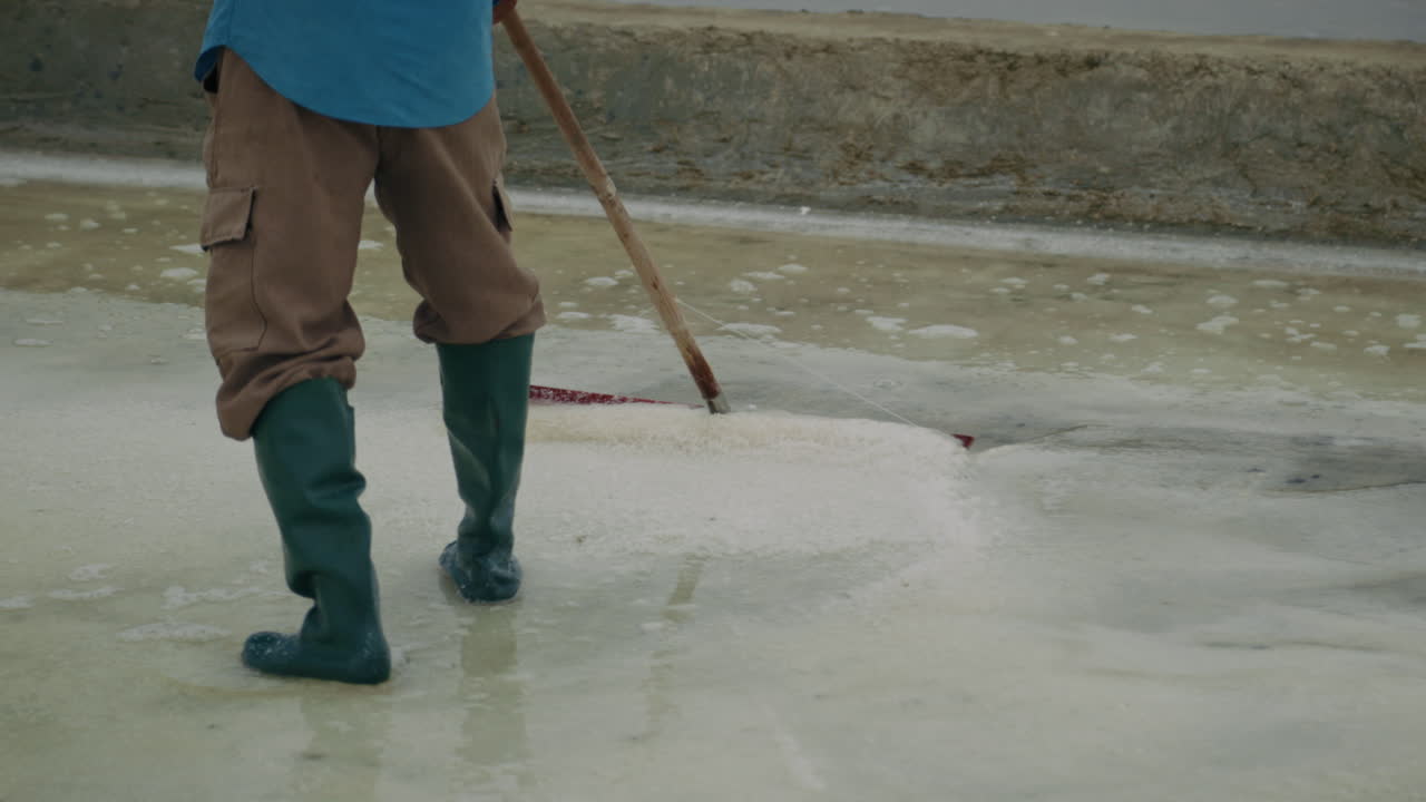 Person raking salt in a salt field