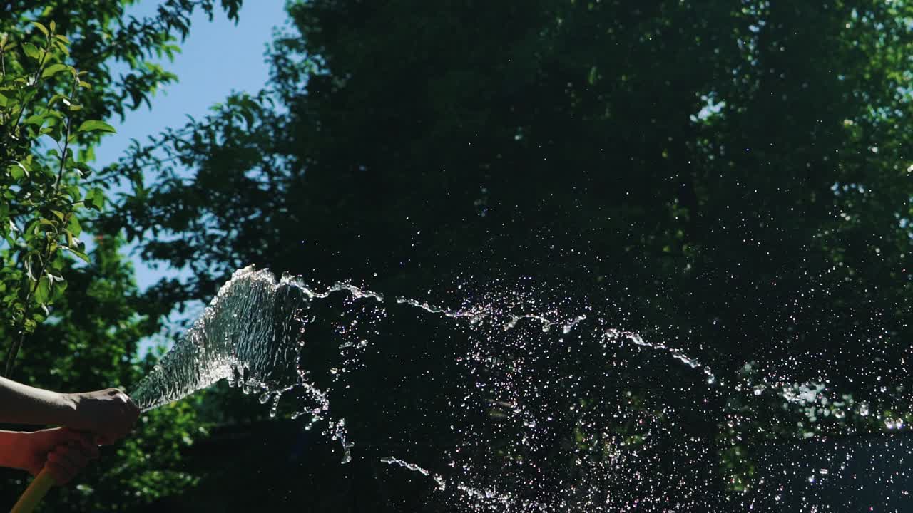 Flow of clean water from a rubber hose. Summer gardening. Slow Motion.