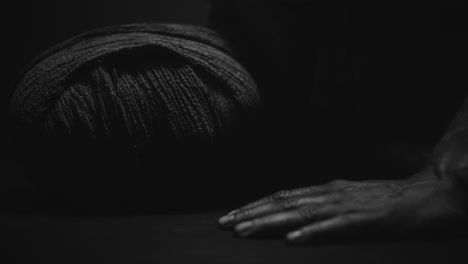 a mummy of a woman on a dark backdrop turns and then lowers her head