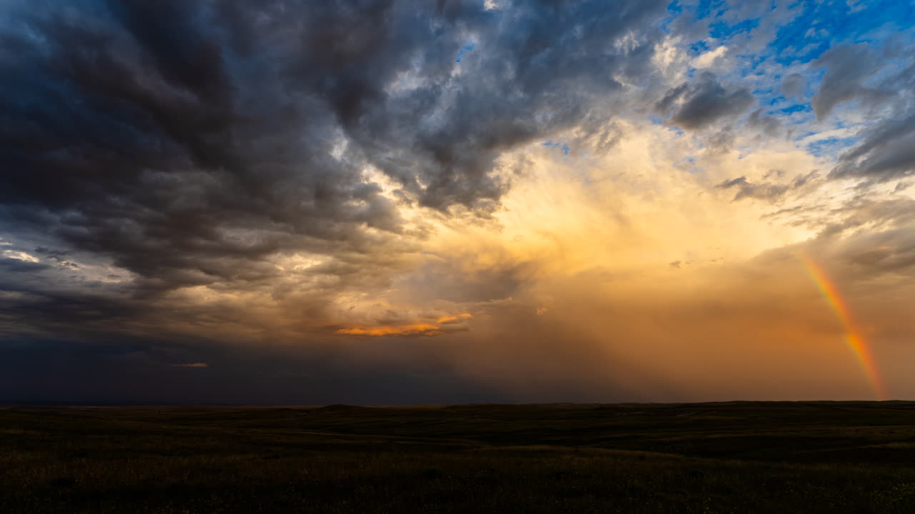 Fiery sunset colors and a bright rainbow in a stormy time lapse