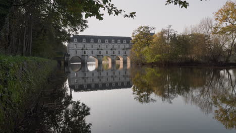 serene view of the cher river reflecting autumn trees near the château de chenonceau in loire valley
