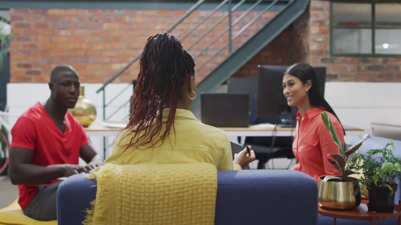 Happy diverse female and male business colleagues using laptops discussing work at meeting