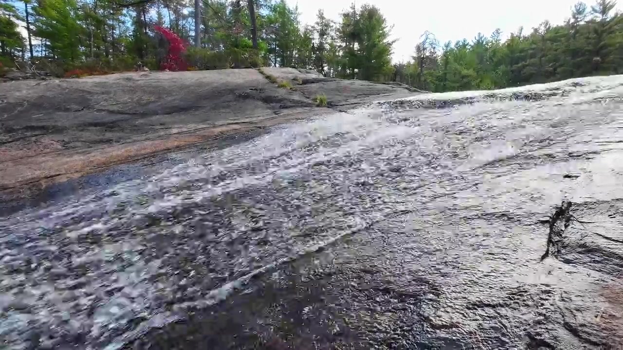 Upward view of High Falls flowing over a broad rock ledge in Algonquin Provincial Park, Ontario, Canada.