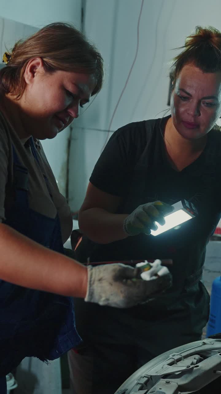 Women Car Mechanics Inspecting a Car Part
