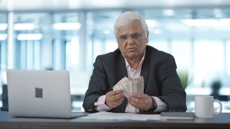 confused indian senior businessman counting money