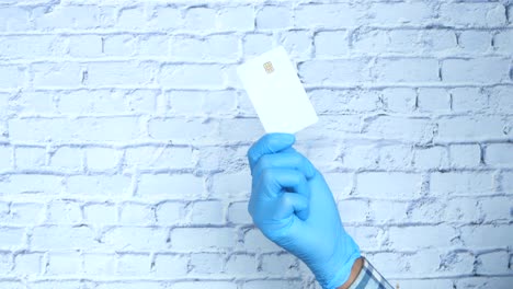 mano con guantes azules sosteniendo una tarjeta de crédito