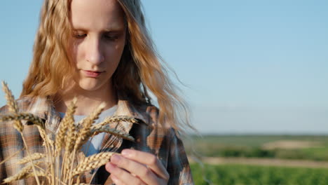 portrait of a teenage girl with spikelets of wheat in her hand. set against a backdrop of picturesque countryside