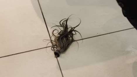 lock of hair falling on tiled floor and picked up