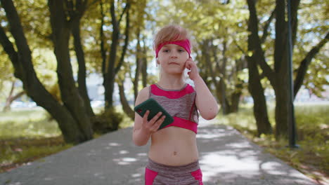 athletic fitness sport runner child girl walking, using smartphone listening music with earphones