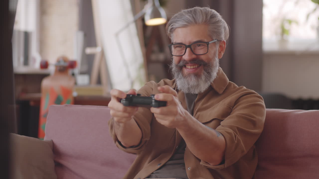 uomo di mezza età eccitato che gioca a videogiochi sulla console