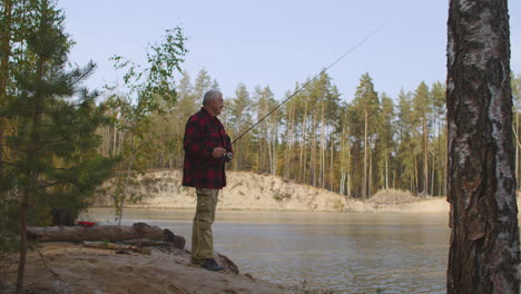 middle-aged man is relaxing in forest fishing on coast of river at weekend male entertainment at nature