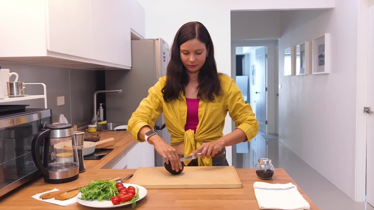 mujer cortando un aguacate en una cocina moderna